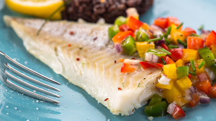 A lightly grilled white fish served with a mix of chopped cooked vegetables