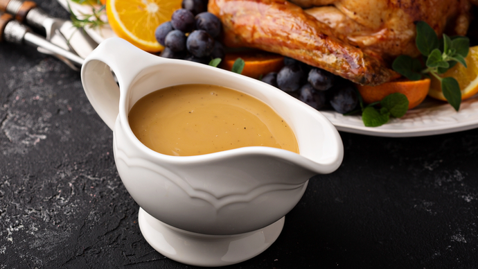 Thick smooth gravy in a white gravy boat ready to be served