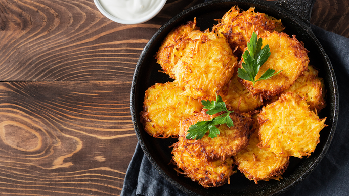 Golden potato hash pieces piled on a plate and topped with garnish