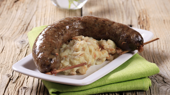 a heap of creamy mashed black pudding on a plate topped with a whole black pudding