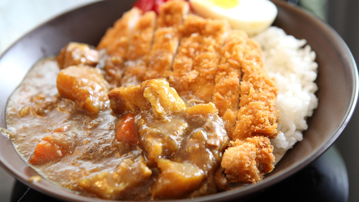 A serving of katsu curry with chicken pieces and white rice