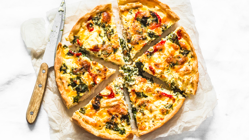 A round pizza cut into quarters topped with leftover leek and potato