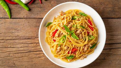 a delicious bowl of noodles stirred in with bright orange and green veggies and mince