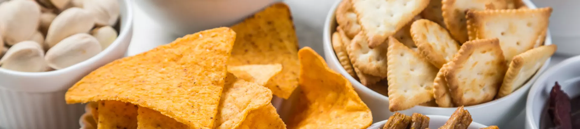 A selection of savoury snacks in small white ceramic bowls.